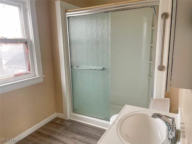 bathroom with wood finished floors, a stall shower, a sink, and baseboards