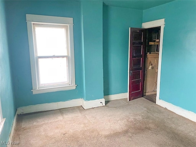 spare room featuring carpet floors and baseboards