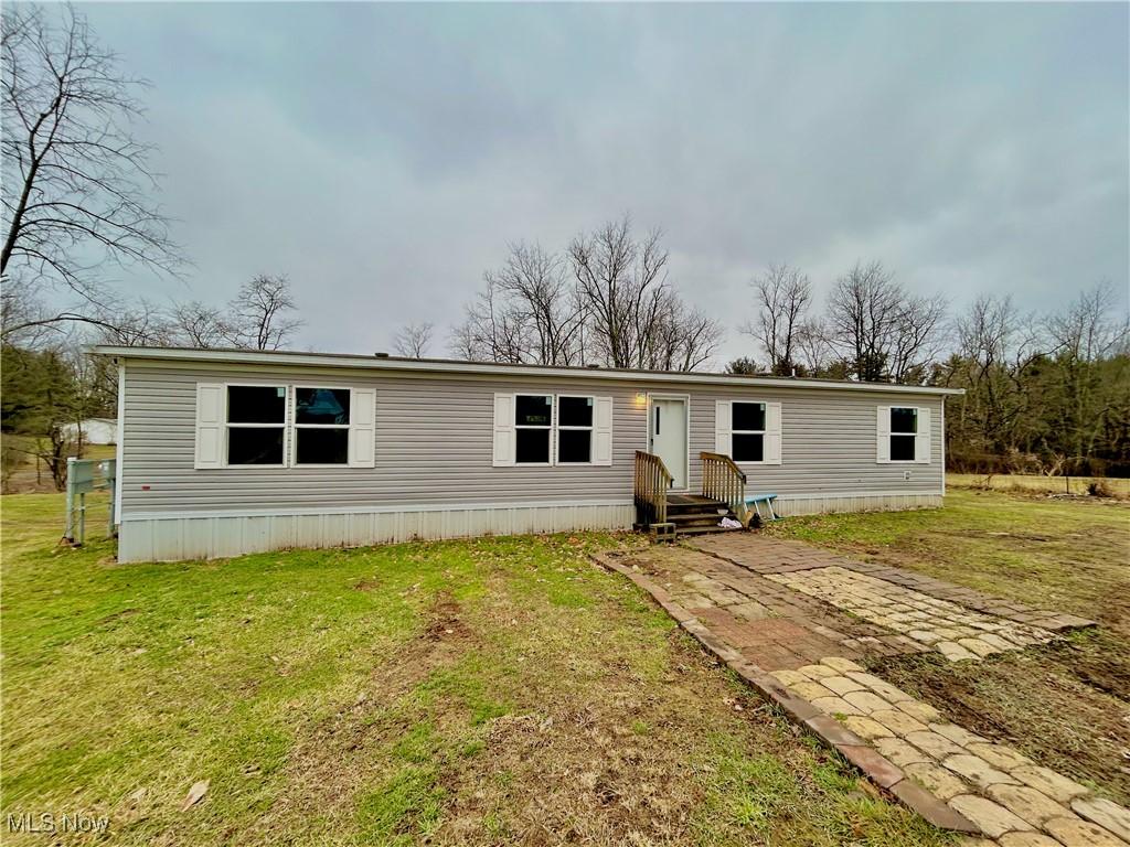 manufactured / mobile home with entry steps and a front lawn