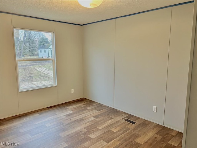 empty room with a textured ceiling and light wood-type flooring