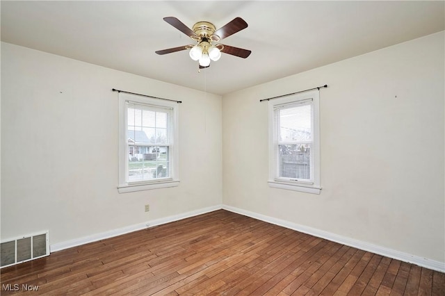 empty room with hardwood / wood-style flooring, a healthy amount of sunlight, and ceiling fan