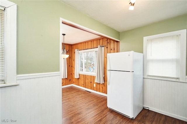 kitchen with white fridge, dark hardwood / wood-style floors, and wooden walls