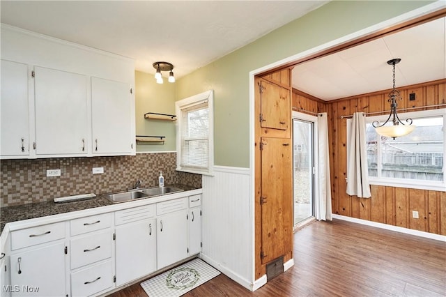 kitchen with sink, dark wood-type flooring, white cabinetry, hanging light fixtures, and decorative backsplash