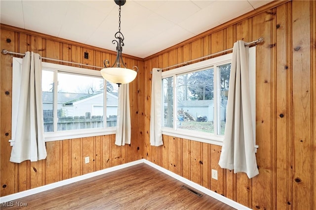 unfurnished dining area with hardwood / wood-style flooring and wood walls