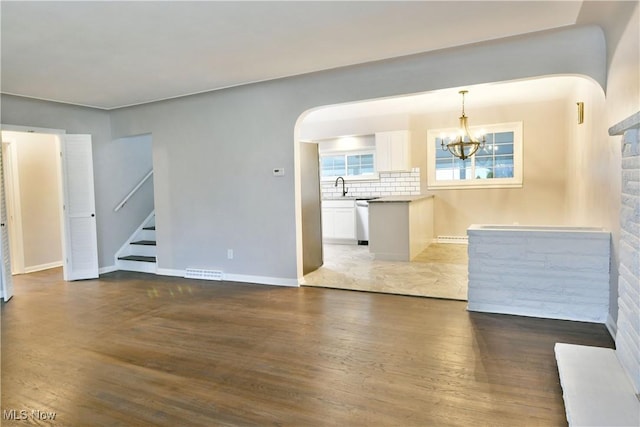 unfurnished living room with a baseboard radiator, dark hardwood / wood-style flooring, sink, and a notable chandelier