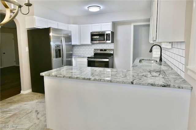 kitchen featuring appliances with stainless steel finishes, white cabinetry, sink, kitchen peninsula, and light stone countertops