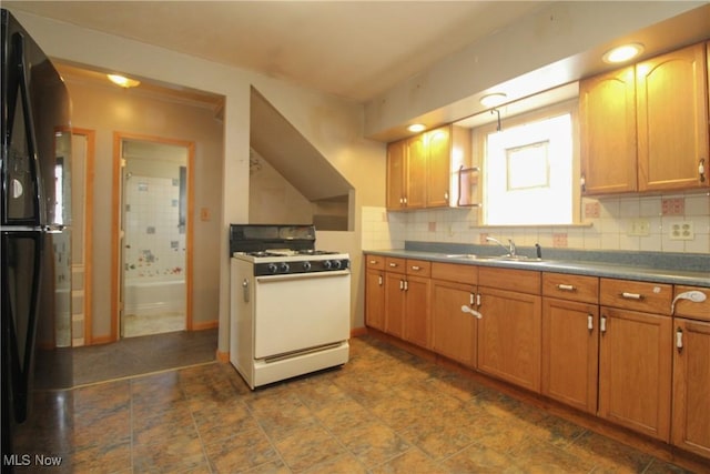 kitchen featuring tasteful backsplash, sink, white gas stove, and black fridge