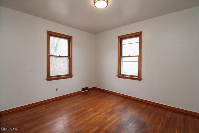 unfurnished room featuring plenty of natural light and dark hardwood / wood-style flooring