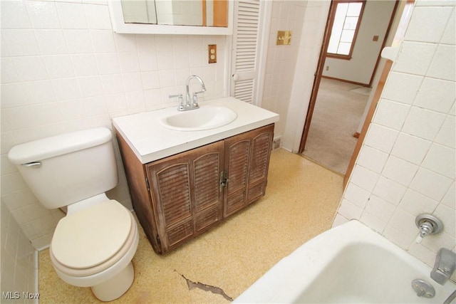 bathroom with vanity, toilet, tile walls, and a tub