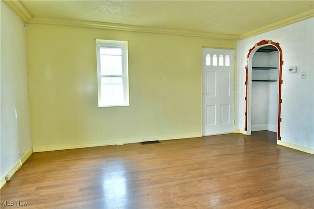 entrance foyer with crown molding, wood-type flooring, and a textured ceiling