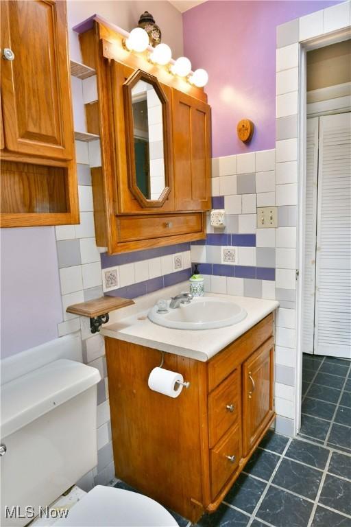 bathroom with vanity, tile walls, and toilet