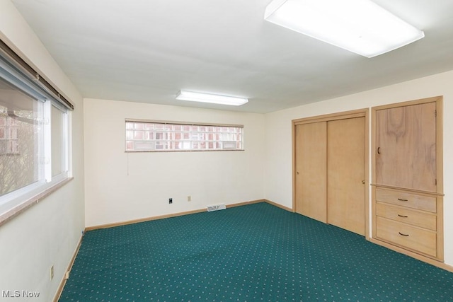 unfurnished bedroom featuring multiple windows, a closet, and dark colored carpet