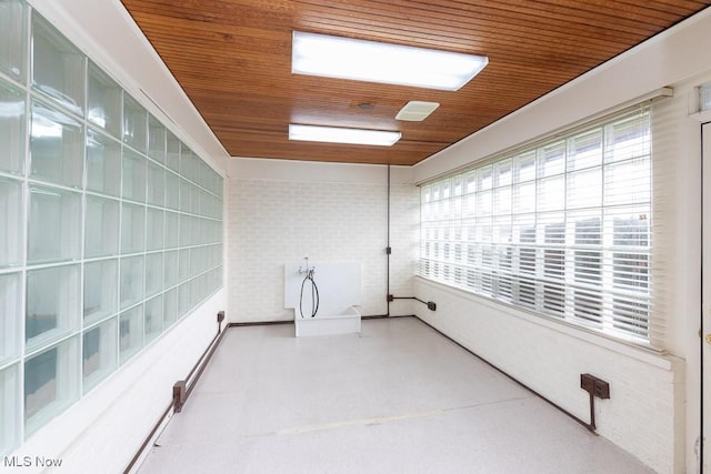 interior space featuring wood ceiling, a wealth of natural light, and brick wall