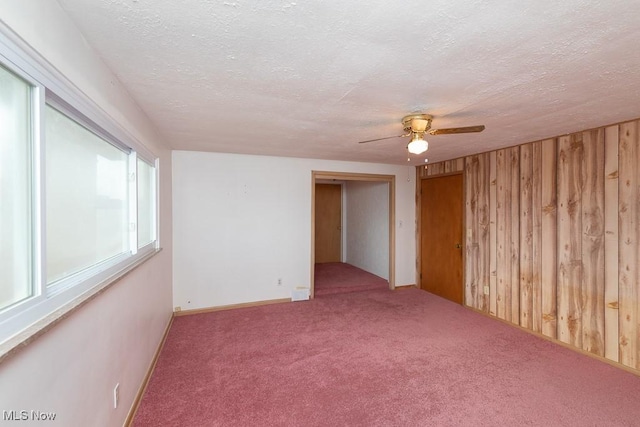 spare room with ceiling fan, wooden walls, a textured ceiling, and carpet flooring