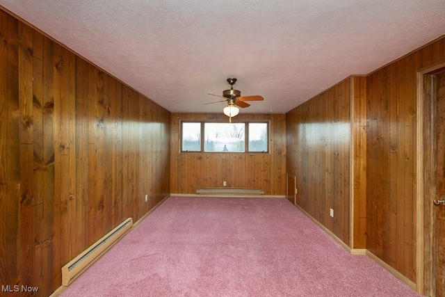 empty room featuring a baseboard radiator, carpet flooring, a textured ceiling, and wooden walls