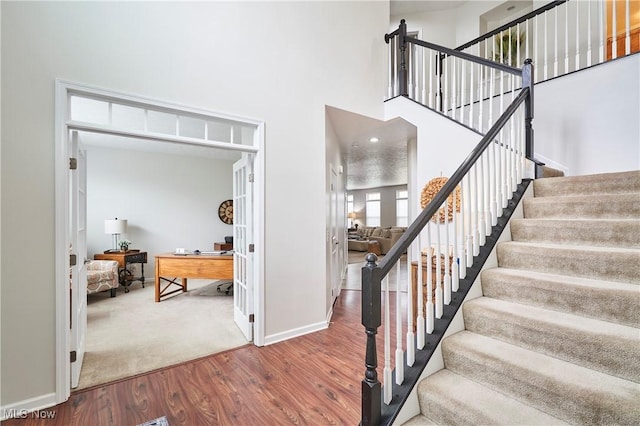 staircase featuring a towering ceiling and hardwood / wood-style floors