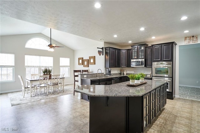 kitchen featuring stainless steel appliances, kitchen peninsula, a healthy amount of sunlight, and stone countertops