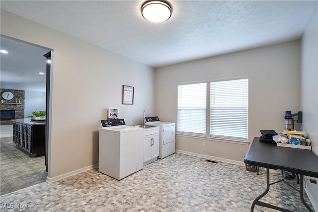 laundry area featuring cabinets, a fireplace, washing machine and dryer, and a textured ceiling