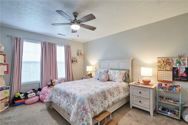 carpeted bedroom with ceiling fan and a textured ceiling