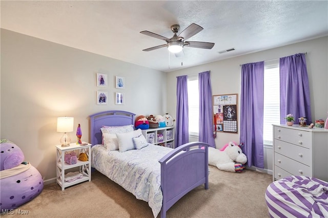 carpeted bedroom with ceiling fan and a textured ceiling