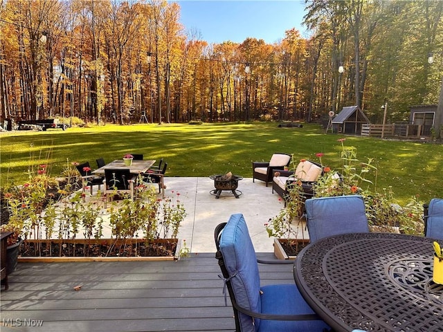 wooden terrace with a lawn and an outdoor fire pit