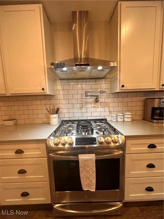 kitchen featuring ventilation hood, decorative backsplash, white cabinets, and stainless steel gas stove