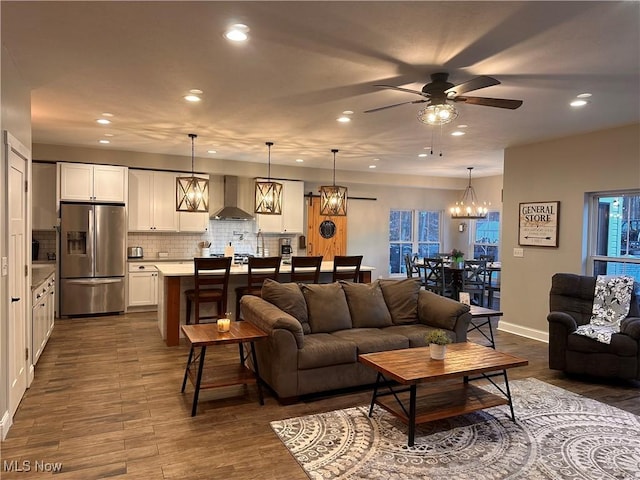 living room with ceiling fan with notable chandelier and dark wood-type flooring