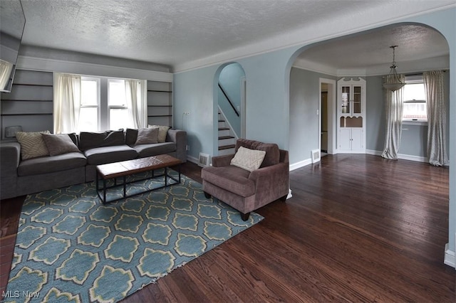 living room with dark wood-type flooring, built in features, and a textured ceiling