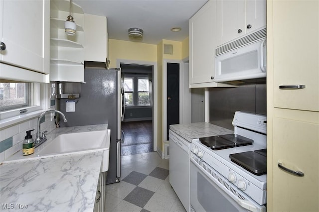 kitchen with sink, backsplash, white cabinets, light stone counters, and white appliances