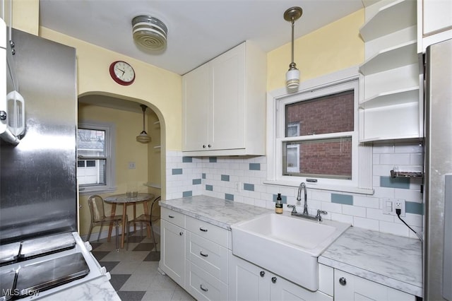 kitchen with light stone counters, sink, tasteful backsplash, and white cabinets