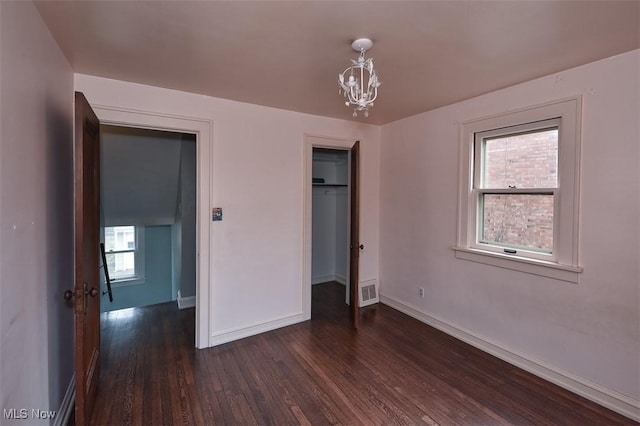 unfurnished bedroom with dark hardwood / wood-style floors, a closet, and a notable chandelier