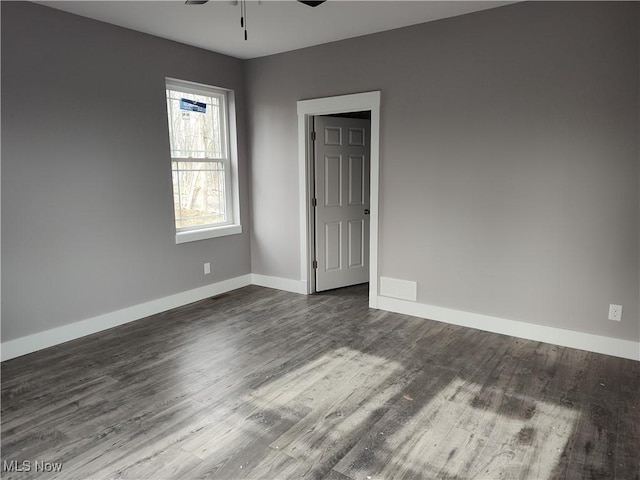 spare room featuring baseboards, dark wood finished floors, and a ceiling fan