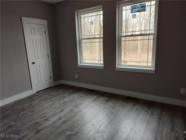 unfurnished room featuring visible vents, baseboards, and wood finished floors