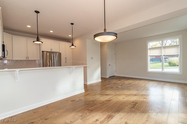 kitchen featuring appliances with stainless steel finishes, a breakfast bar area, white cabinets, and light hardwood / wood-style flooring