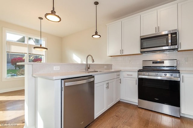 kitchen featuring hanging light fixtures, white cabinets, and appliances with stainless steel finishes