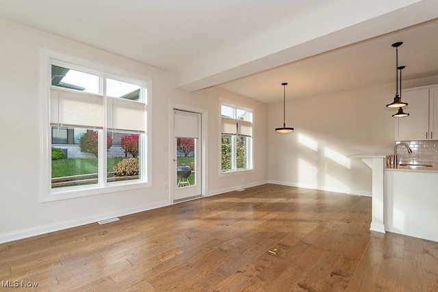 unfurnished living room featuring sink, a wealth of natural light, and wood-type flooring