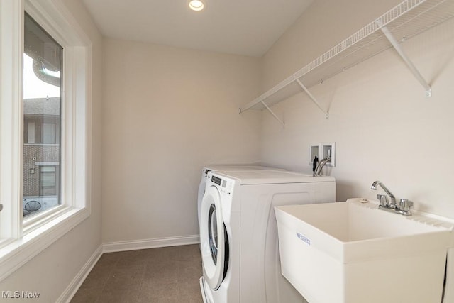 clothes washing area with separate washer and dryer, sink, and a wealth of natural light