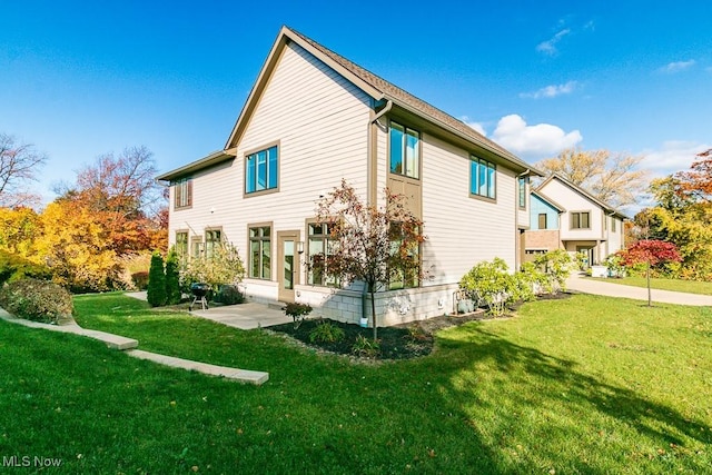 rear view of property featuring a lawn and a patio area