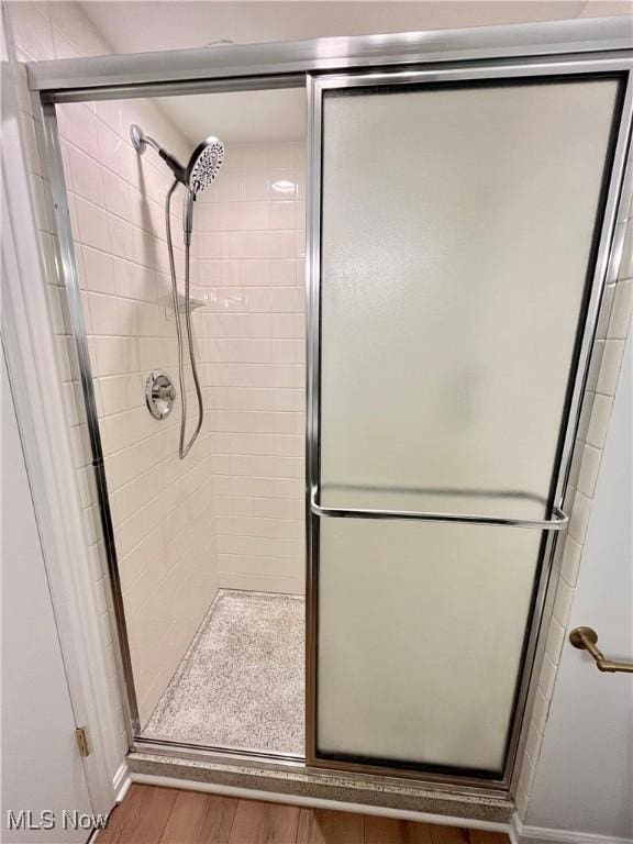 bathroom featuring hardwood / wood-style floors and a shower with shower door