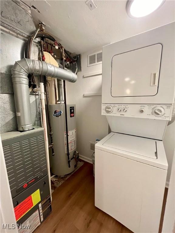 washroom featuring dark hardwood / wood-style floors, gas water heater, and stacked washer and clothes dryer