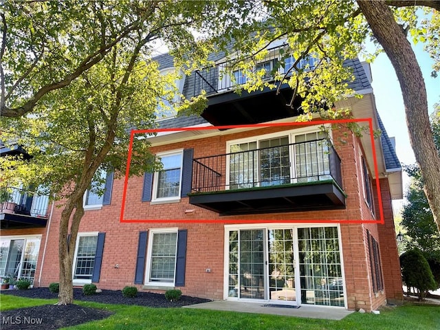 rear view of house with a balcony and a lawn