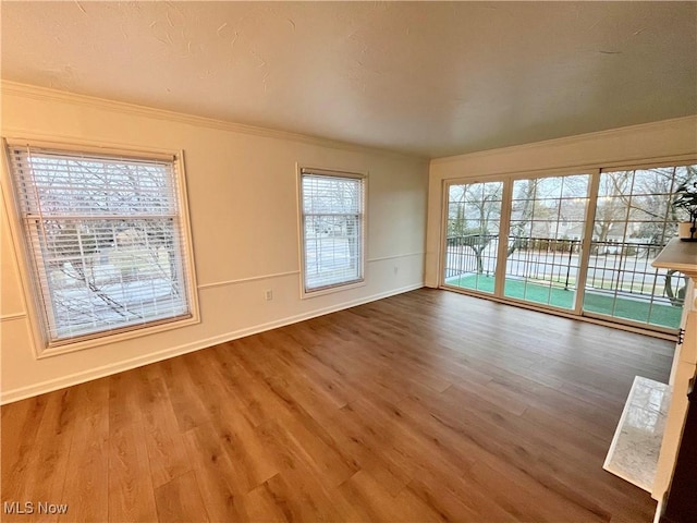 empty room with a healthy amount of sunlight, wood-type flooring, and crown molding