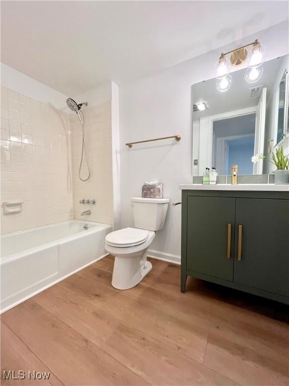 full bathroom with hardwood / wood-style floors, vanity, toilet, and tiled shower / bath combo