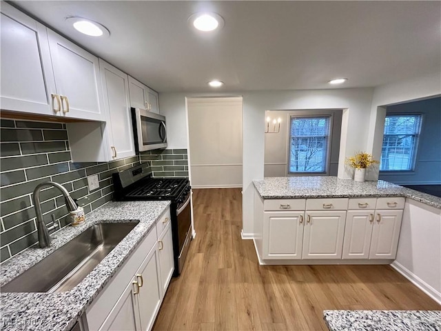 kitchen with white cabinetry, light hardwood / wood-style flooring, sink, appliances with stainless steel finishes, and decorative backsplash