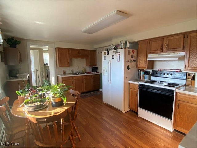 kitchen with wood-type flooring, white fridge with ice dispenser, sink, and electric range