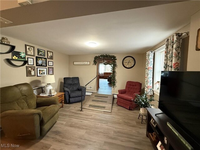 living room featuring a baseboard radiator and light hardwood / wood-style flooring