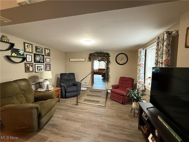 living area with light wood-type flooring and a baseboard heating unit