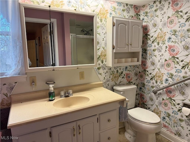 bathroom featuring wallpapered walls, toilet, vanity, and a shower with door