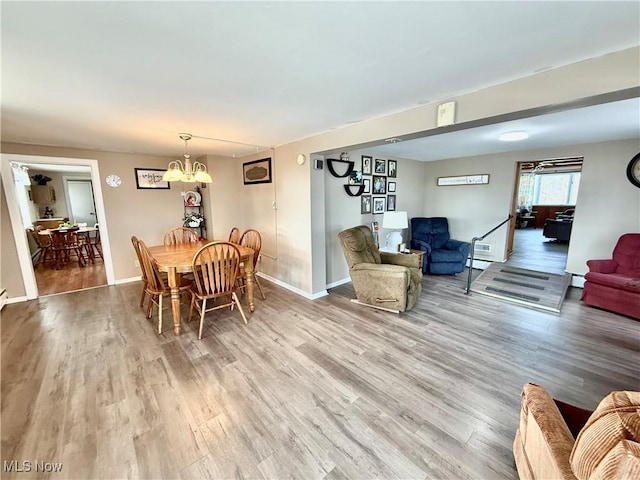 dining space with a chandelier, a baseboard heating unit, baseboards, and wood finished floors