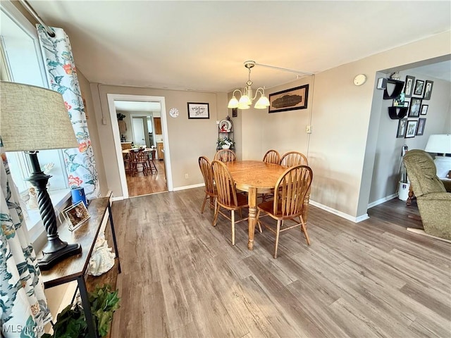 dining space with a notable chandelier, wood finished floors, baseboards, and a wealth of natural light